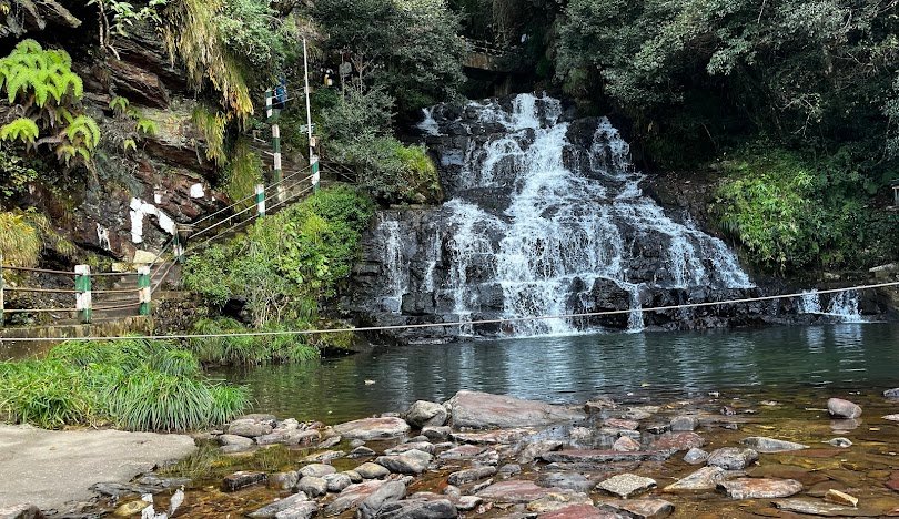 Scenic view of Meghalaya, the “Abode of Clouds,” with lush green hills, cascading waterfalls, and mist-covered landscapes.