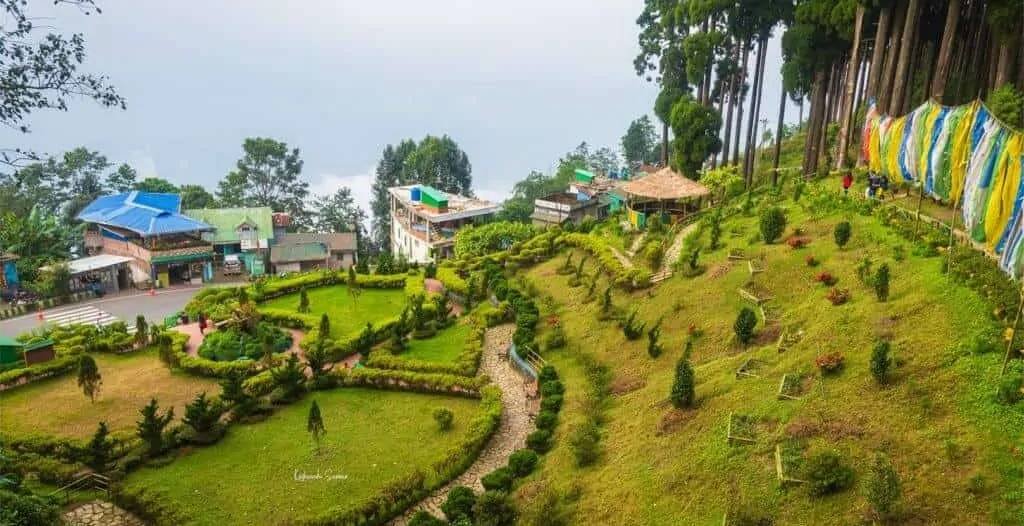  Scenic view of Tinchuley village near Darjeeling with tea gardens, orange orchards, and the Kanchenjunga mountain in the background.